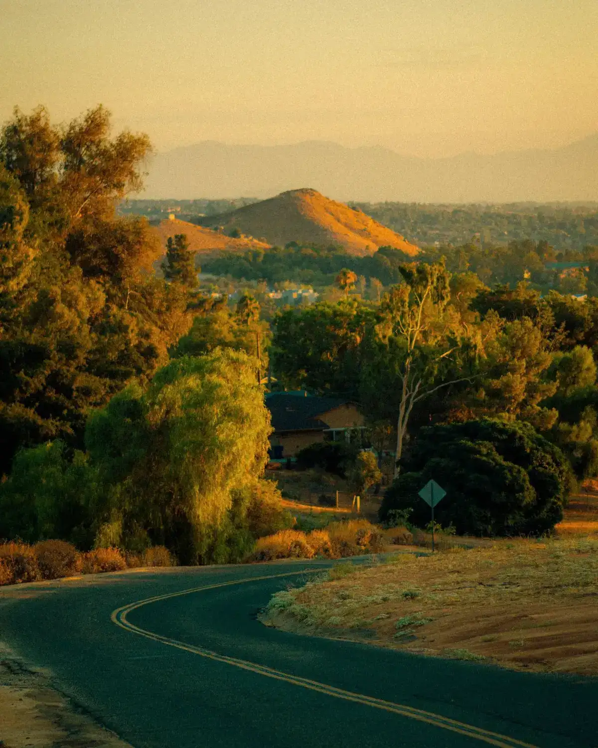 Golden-hour view of a winding road through dry hills in inland Southern California